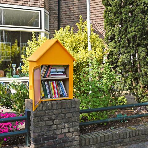 Gele mini-bibliotheek met boeken in straat