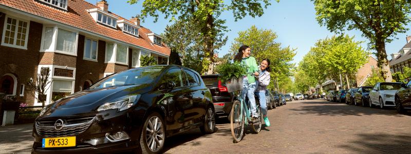 twee meisjes fietsen lachend door de straat