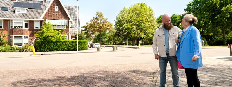 man helpt oudere vrouw met oversteken op straat