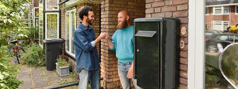 mannen geven elkaar een boks bij voordeur