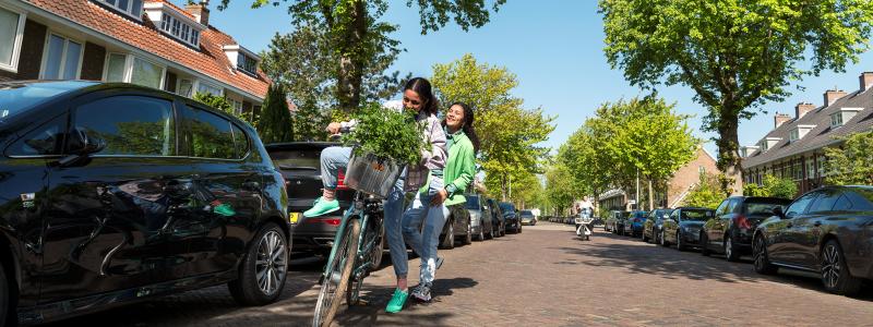 twee meisjes fietsen lachend door de straat