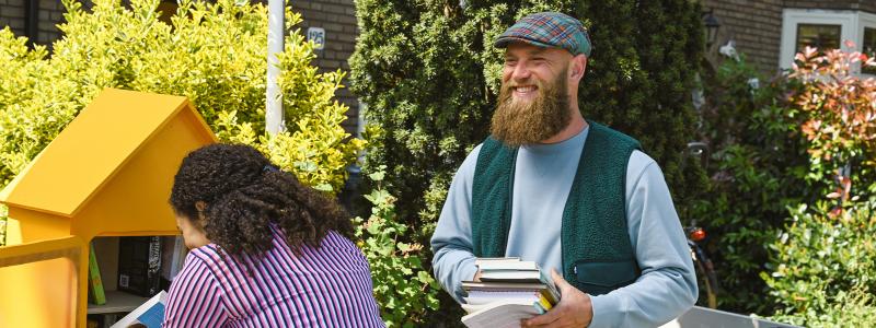 meisje en man bekijken boeken in minibieb op straat